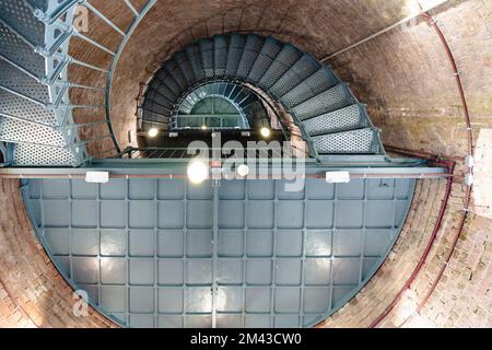 Image looking up toward ceiling of a green spiral, circular metal, iron staircase with red brick walls in a lighthouse. Stock Photo