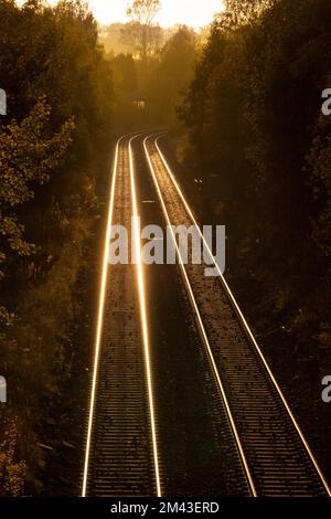 Sunset on the Ribble Valley railway line at Gisburn with a golden glint along the track Stock Photo