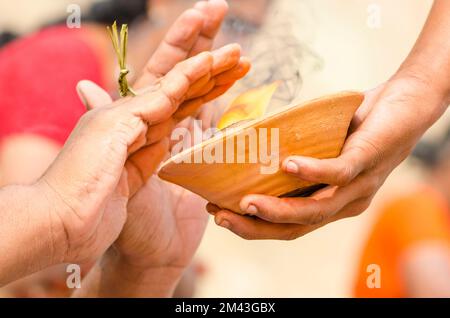 Hands over fire is part of the ritual to pray farewell for the soul of a died person, seen at the ghats Stock Photo