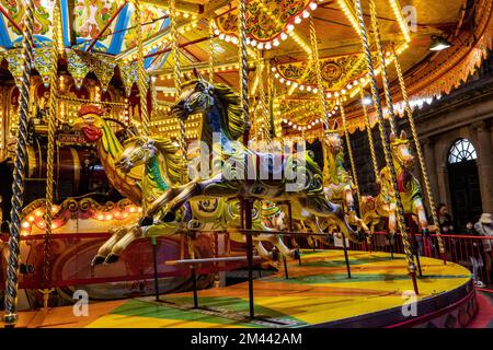 Brightly coloured fairground carousel with galloping ponies. At Christmas Market in Bath UK Stock Photo