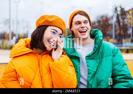 Multiracial young couple of lovers dating outdoors in winter, wearing winter jackets and having fun - Multiethnic millennials bonding in a urban area, Stock Photo