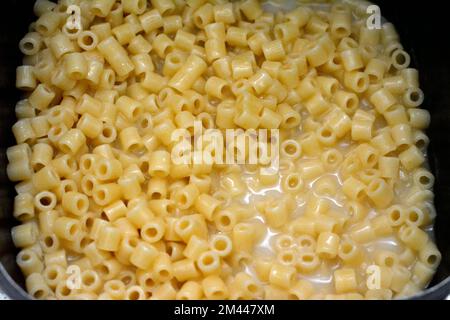 boiling ring macaroni pasta in hot water ready to put tomato sauce on it, Italian recipe of macaroni ready to be served with any type of sauce and gar Stock Photo