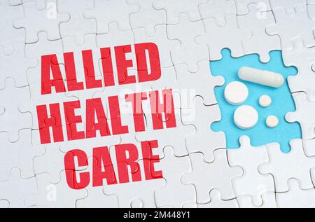 Medical concept. On the puzzles there is an inscription - Allied Health Care, on a blue background pills. Stock Photo