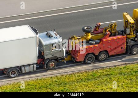 Powerful heavy duty big rig mobile tow semi truck emergency lights and towing equipment prepare tow broken white semi tractor standing out service hig Stock Photo