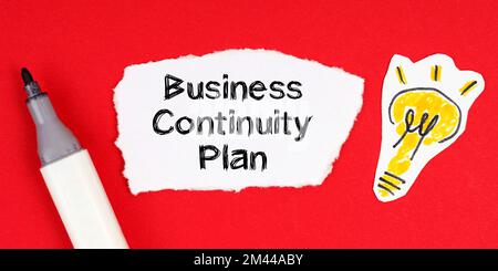 Business concept and idea. On a red surface lie a marker, a drawing of a light bulb and torn paper with the inscription - Business Continuity Plan Stock Photo