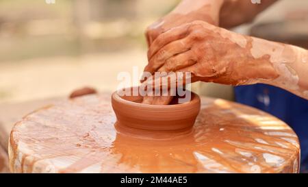 unrecognizable pottery woman working with pottery wheel in cozy workshop creates vase or mug, creative people Stock Photo