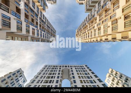 view up from ground to blue sky among skyscrapers, look at house from bottom up Stock Photo