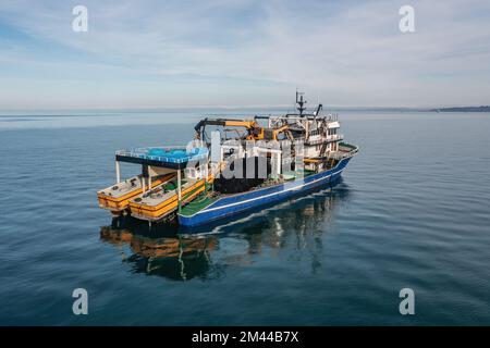 Fishing boat aerial view from drone on sea surface. Fishing and seafood industry. Stock Photo