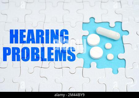 Medical concept. On the puzzles there is an inscription - Hearing Problems, on a blue background pills. Stock Photo