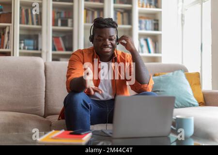 Happy millennial african american man student attending webinar, using laptop Stock Photo