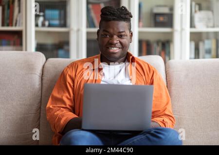 Smiling african american guy using modern laptop at home Stock Photo