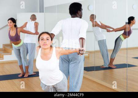 Couples practicing yoga with partner at studio Stock Photo