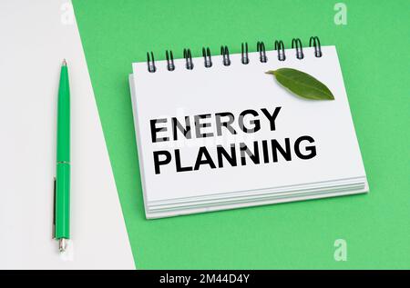 Ecological concept. On a white-green background lies a pen and a notepad with the inscription - Energy Planning. There is a green leaf of a plant on t Stock Photo