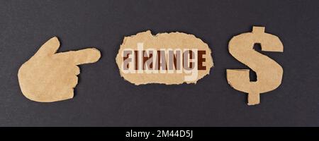 Economy and finance concept. On a black surface, a figure of a hand, a dollar symbol and a torn cardboard with the inscription - FINANCE Stock Photo