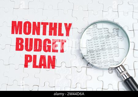 Business concept. There is a magnifying glass on the puzzles, next to it is written - Monthly budget plan Stock Photo