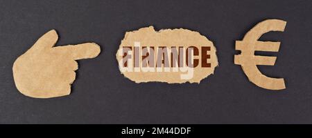 Economy and finance concept. On a black surface, a figure of a hand, a euro symbol and a torn cardboard with the inscription - FINANCE Stock Photo