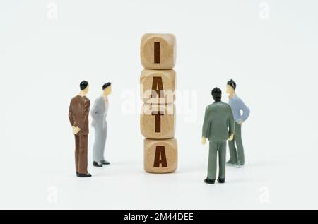 Business and finance concept. On a white background, figures of businessmen look at wooden cubes with the inscription - IATA Stock Photo