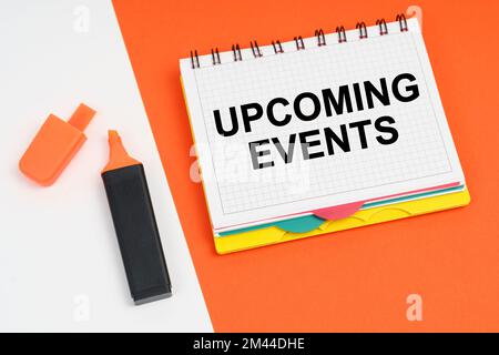 Business and finance concept. On a white-orange surface lies a marker and a notepad with the inscription - UPCOMING EVENTS Stock Photo