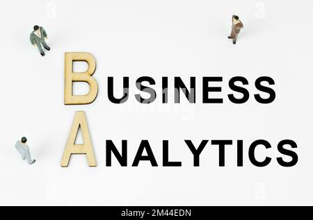 Economy and business concept. On a white background, figures of businessmen, wooden letters and the inscription - BUSINESS ANALYTICS Stock Photo