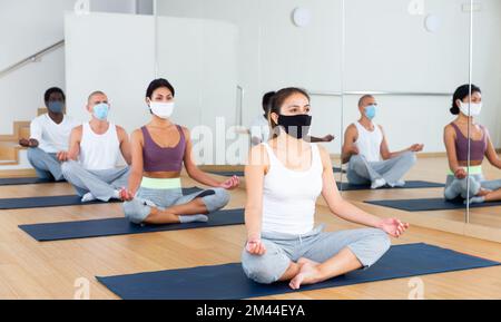 Group of people in protective masks practicing yoga poses Stock Photo