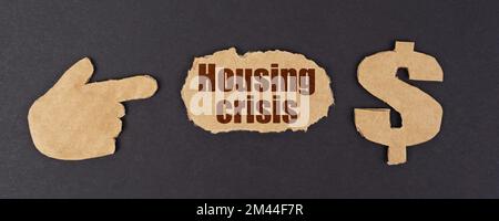 Economy and finance concept. On a black surface, a figure of a hand, a dollar symbol and a torn cardboard with the inscription - Housing Crisis Stock Photo