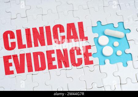 Medical concept. On the puzzles there is an inscription - Clinical Evidence, on a blue background pills. Stock Photo