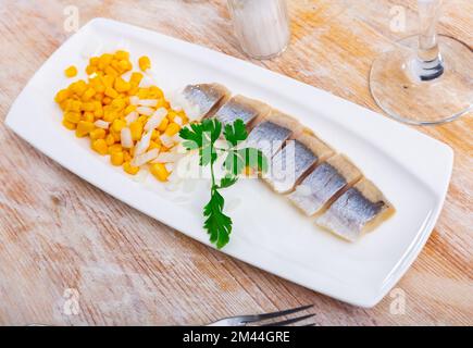 Slices of spicy marinated herring fillet with corn and onion Stock Photo