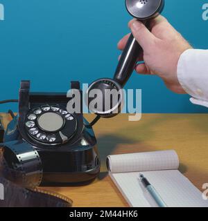 Take the phone. Old telephone set on a wooden table, notepad, ink pen Stock Photo