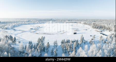 Aerial view of snow covered forest around beautiful lake. Stock Photo