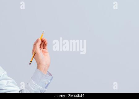 Hand with a pencil pointing at a blank space. Male hand holding a pencil on a blank. Man fingers holding a pencil with blank space. Person's hands Stock Photo