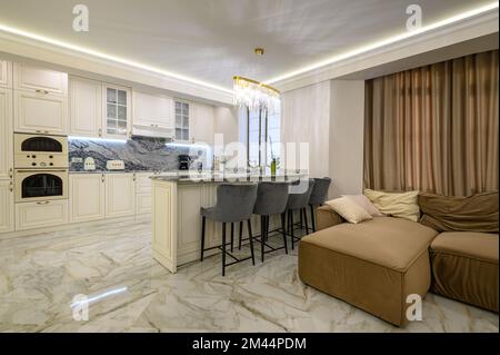 Studio apartment with inviting interior and cream-colored classic kitchen featuring island for dining Stock Photo