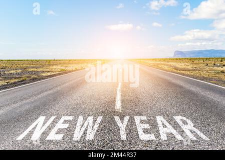 New Year ahead. Conceptual image of a straight road to horizon with the phrase new Year painted on asphalt. Stock Photo