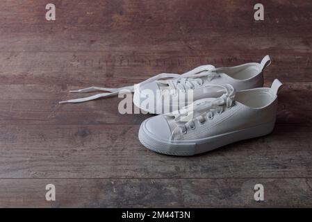 White children sneakers on a old textured wood background Stock Photo