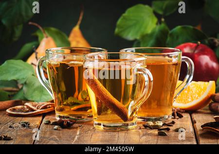 Mulled Cider glass cups: apple, pear and orange flavored  hot cider with spices. Fermented low alcohol cocktail  fruit drink on ustic wooden table. Ba Stock Photo