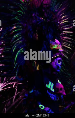 person dressed for the day of the dead in prehispanic neon costume, night reflections Stock Photo