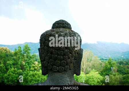 The back of the Borobudur Buddha head overlooking the landscape of Indonesia Stock Photo