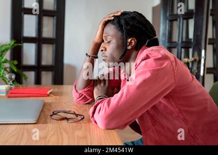 Exhausted overworked remote employee sitting with closed eyes at workplace, suffering from headache Stock Photo