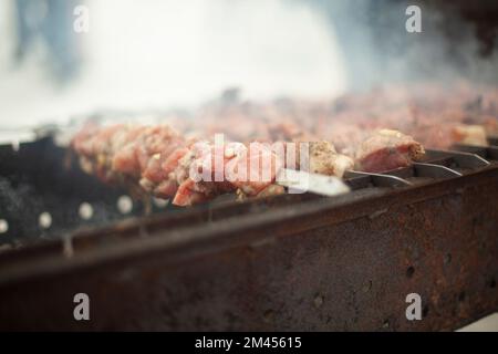 Frying meat on fire. Meat strung on blade. Outdoor kitchen. Fatty food. Stock Photo