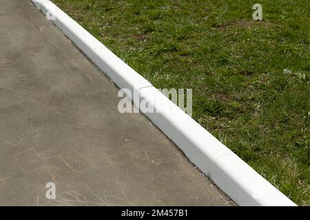 Painted curb. White curb on road. Landscaping in city. White paint. Stock Photo