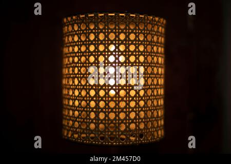 Lamp in dark. Wooden lampshade around incandescent lamp. Minion glows. Stock Photo