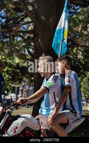 La Plata, Buenos Aires, Argentina - December 18, 2022: A man and a boy with an Argentine flag on a motorbike during the celebration of Argentina winni Stock Photo