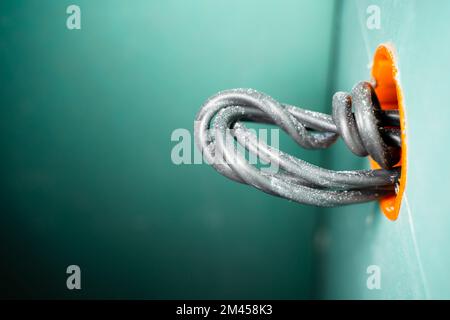 Close-up of a thick black wire sticking out of an orange round drywall socket. Mortgage for a socket or switch with a wire. Electrical wiring for repa Stock Photo
