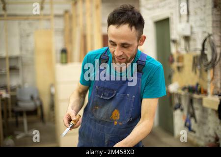 Guy smiles at work. Man in work clothes. Carpentry workshop worker. Stock Photo