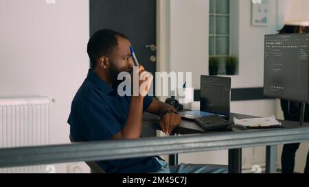Pensive african american programer working on code development and brainstorming ideas to create html script. Software developer thinking about database server in it agency office. Stock Photo