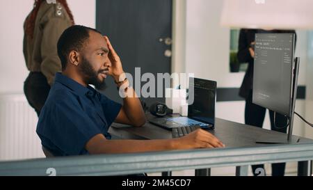 Software programer writing program code to develop database system in front of computer, displaying artificial intelligence algorithm. Developer coding html script on terminal window. Handheld shot. Stock Photo