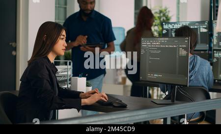 Asian programer typing big data code on computer to work on app developing program, using html script. IT system engineer writing ai algorithm and sitting at desk in it startup company. Stock Photo