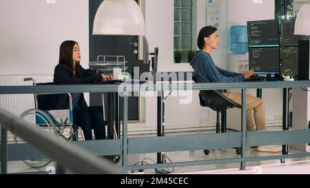 Database programer with physical disability writing code on computer screen, coding artificial intelligence algorithm. Engineer with impairment programming database on terminal window. Stock Photo