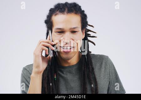 Really I had no idea. Studio shot of a young man using a mobile phone against a grey background. Stock Photo