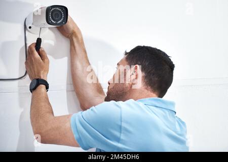 With this new camera youll be able to view everything. a mature man installing a security camera on a building. Stock Photo