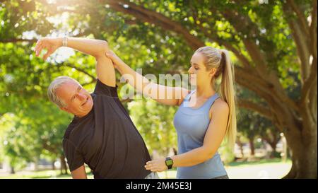And now we stretch to the side...a young instructor guiding a senior man in a yoga class. Stock Photo